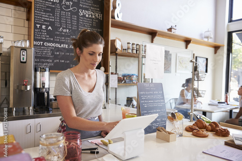 Woman working on the till at a coffee shop, wide angle