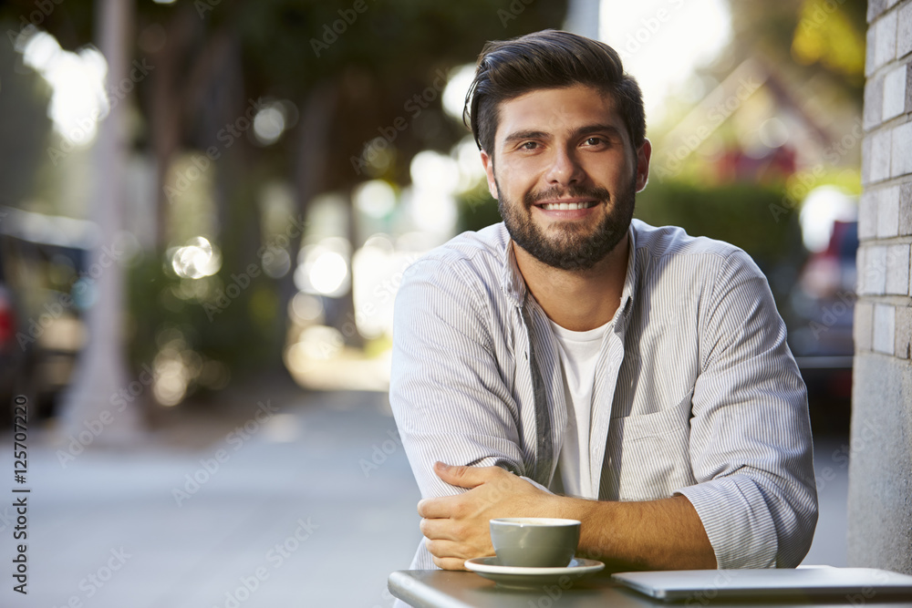 Bearded adult man with laptop sitting at table outside cafe Bearded adult man with laptop sitting at table outside cafe
