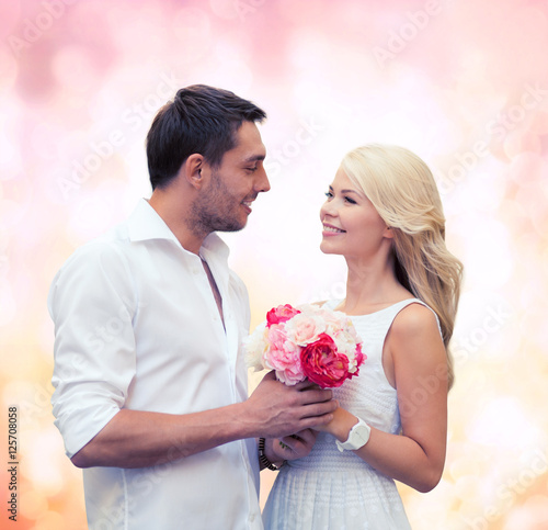 happy couple with flowers over lights background