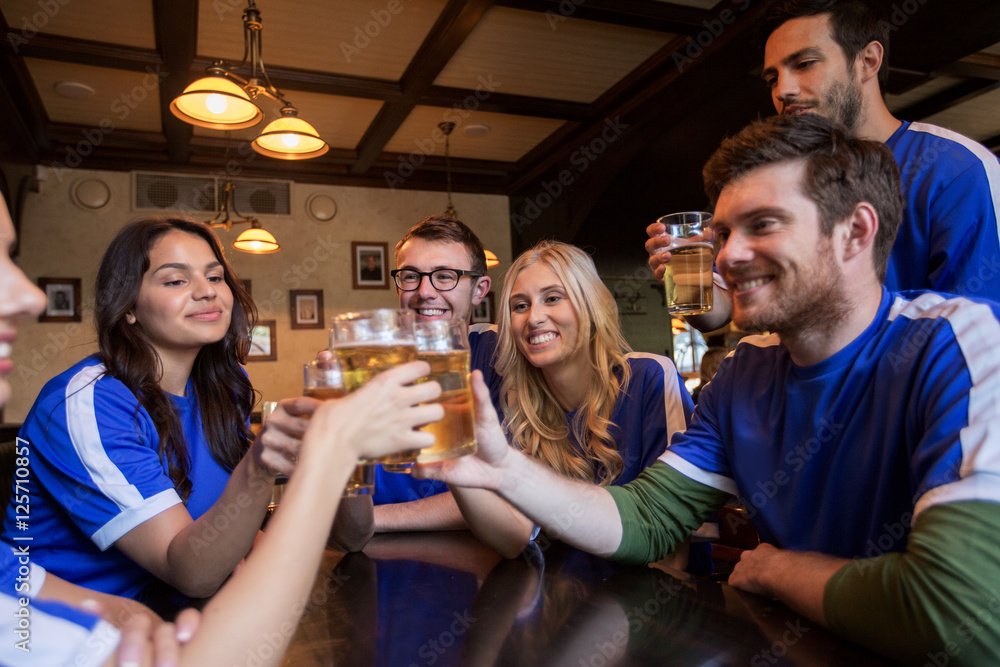 Obraz premium football fans clinking beer glasses at sport bar