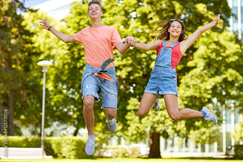 happy teenage couple jumping at summer park