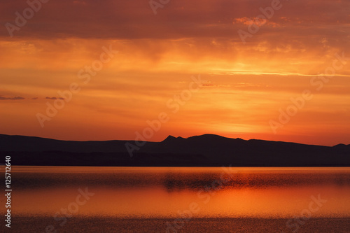 Russia. Khakassia. Sunrise on the Lake Shire. On the horizon  the silhouette of hills and mountains.