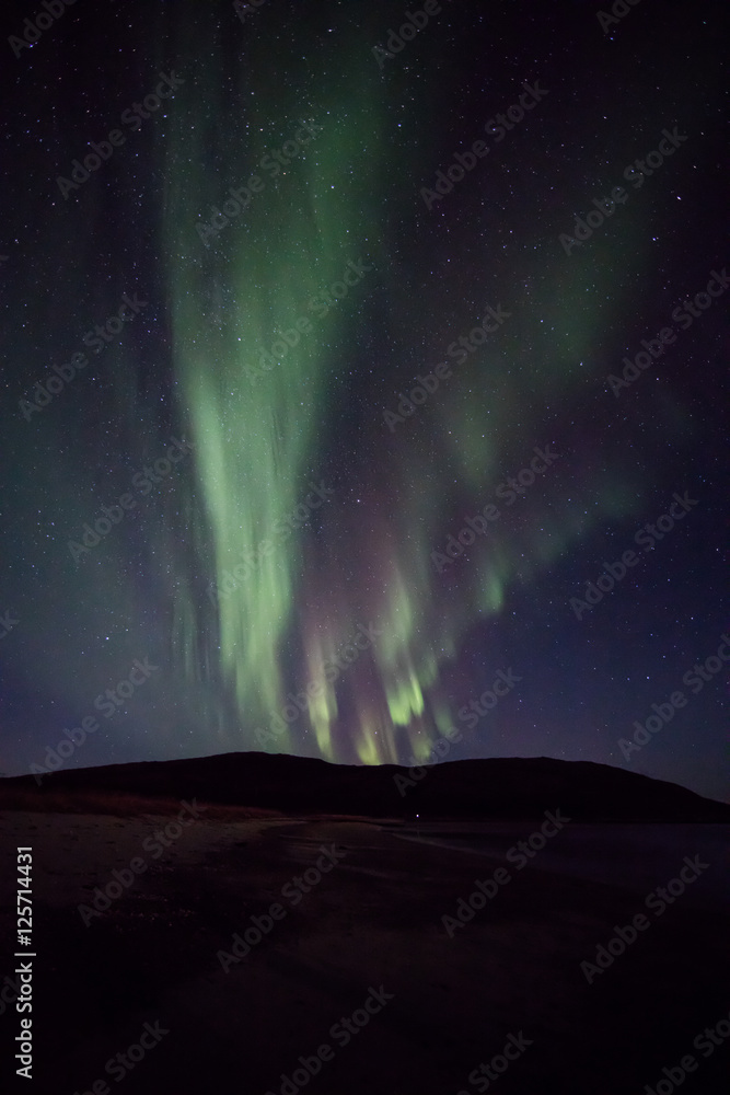Gentle auroras explode from mountain near Tromso