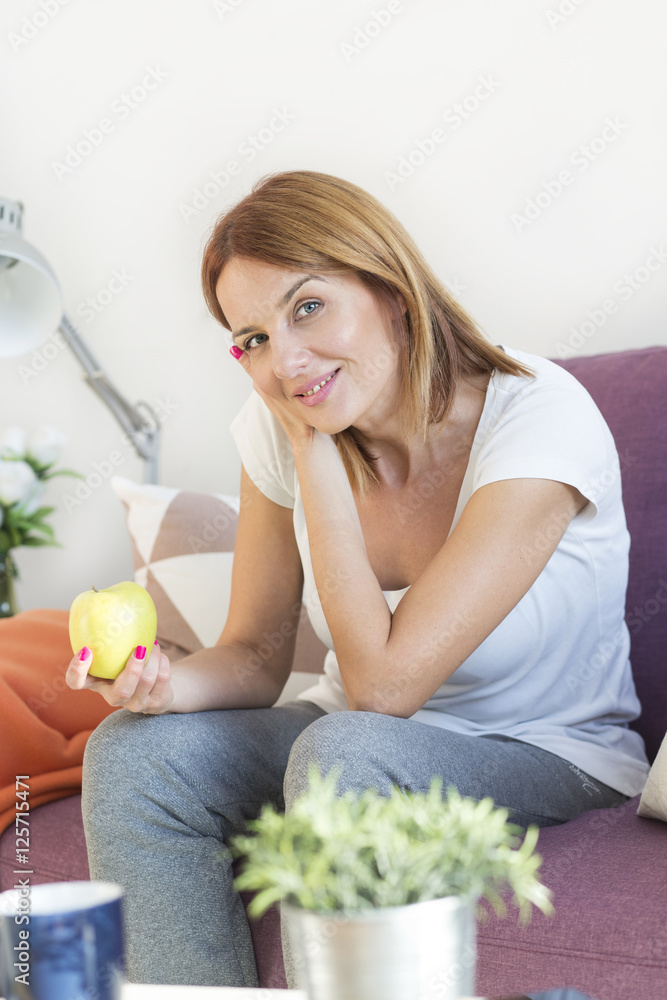Young red hair woman sitting on the couch in living room eating