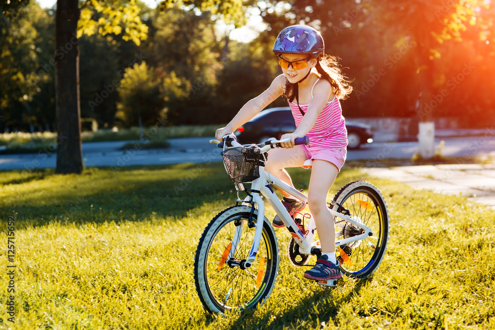 Fototapeta premium happy child girl riding bicycle in summer sunset