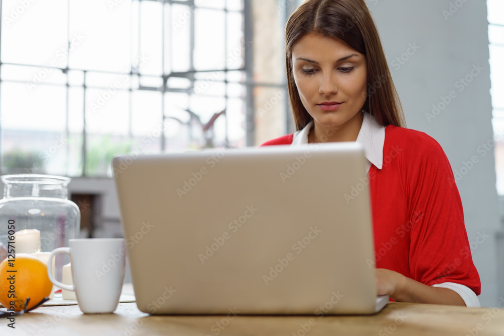 frau sitzt zuhause am tisch und schaut auf ihr notebook frau sitzt zuhause am tisch und schaut auf ihr notebook
