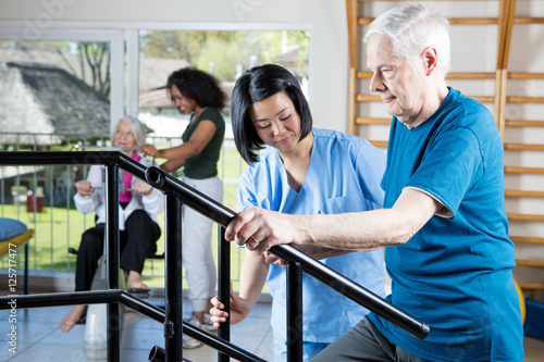 Senior citizens working out at gym with multi racial trainers he