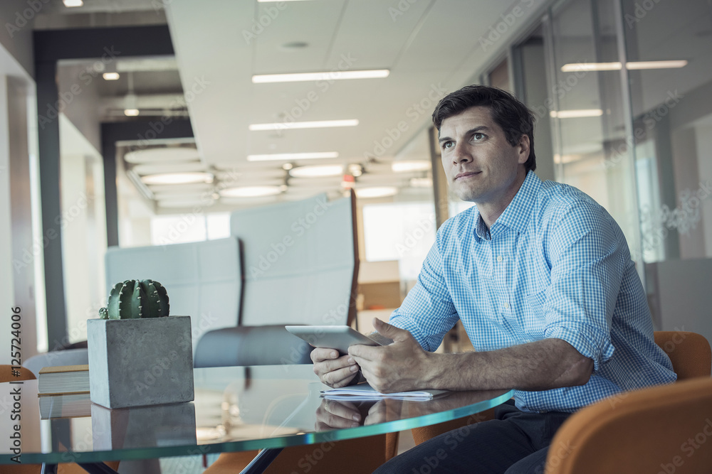 Businessman sitting in office, using digital tablet Businessman sitting in office, using digital tablet