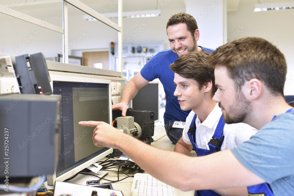 Technical instructor and students looking at computer screen Technical instructor and students looking at computer screen