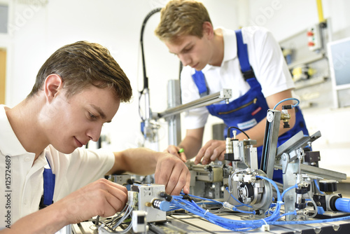 Two students working with pneumatics component parts photo
