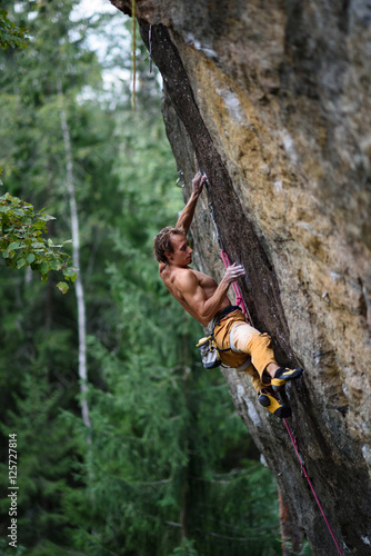 Outdoor sport. Rock climber dangles in midair as he struggles to climb a challenging cliff.