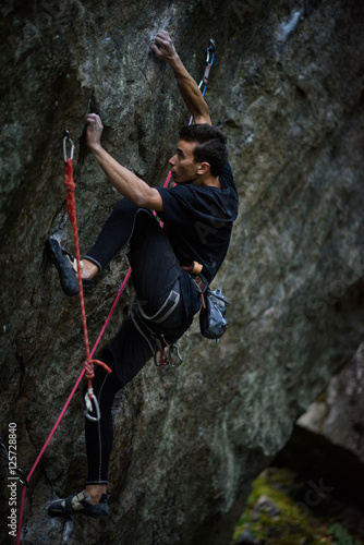 Extreme sport climbing. Young male rock climber on a rock wall.