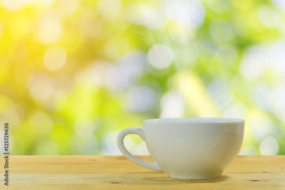 Close up of the white coffee mug on a wooden floor with a beautiful green nature background. Close up of the white coffee mug on a wooden floor with a beautiful green nature background.