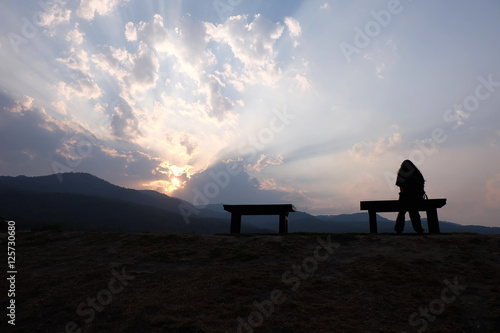 Silhouette of single adult woman watching warm sunset.