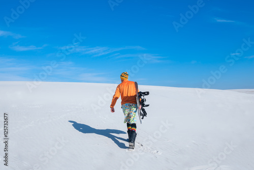 Sand boarder walking along sand dunes