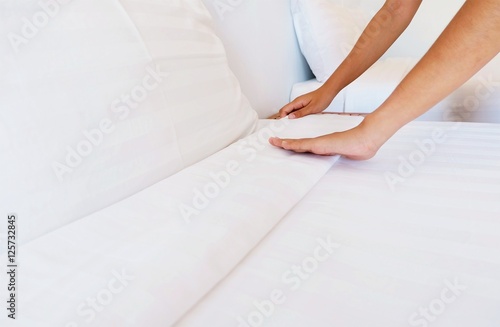 woman hands set up white bed sheet in hotel room