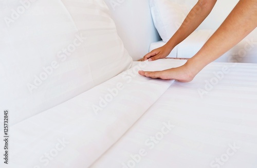 woman hands set up white bed sheet in hotel room
