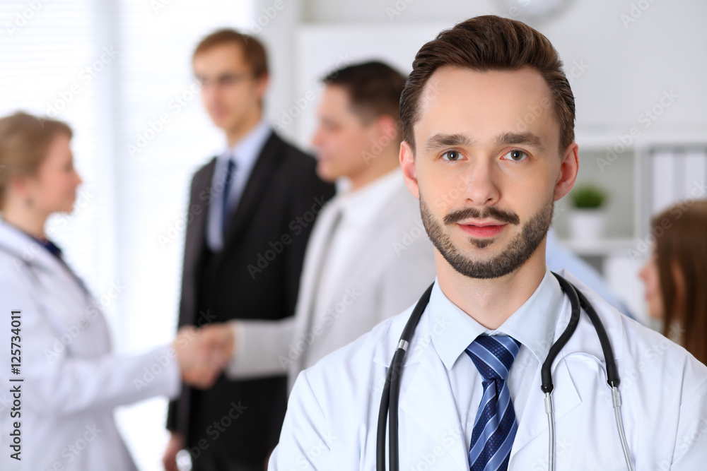 Friendly male doctor on the background doctor and patient shaking hands. Medical trust and ethics concept Friendly male doctor on the background doctor and patient shaking hands. Medical trust and ethics concept