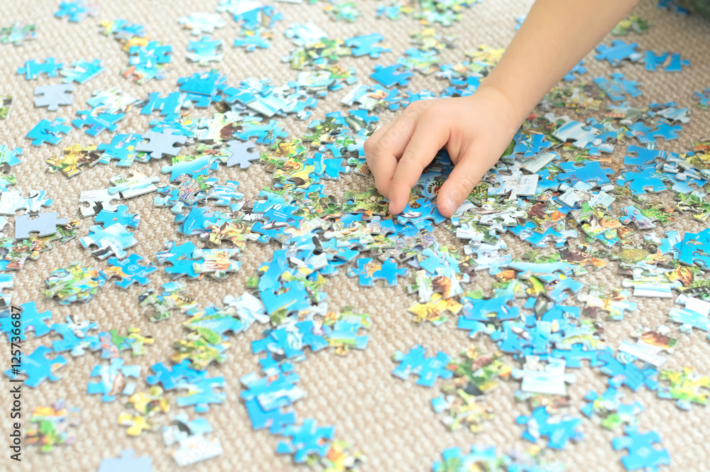 Child hand playing complex puzzle Child hand playing complex puzzle