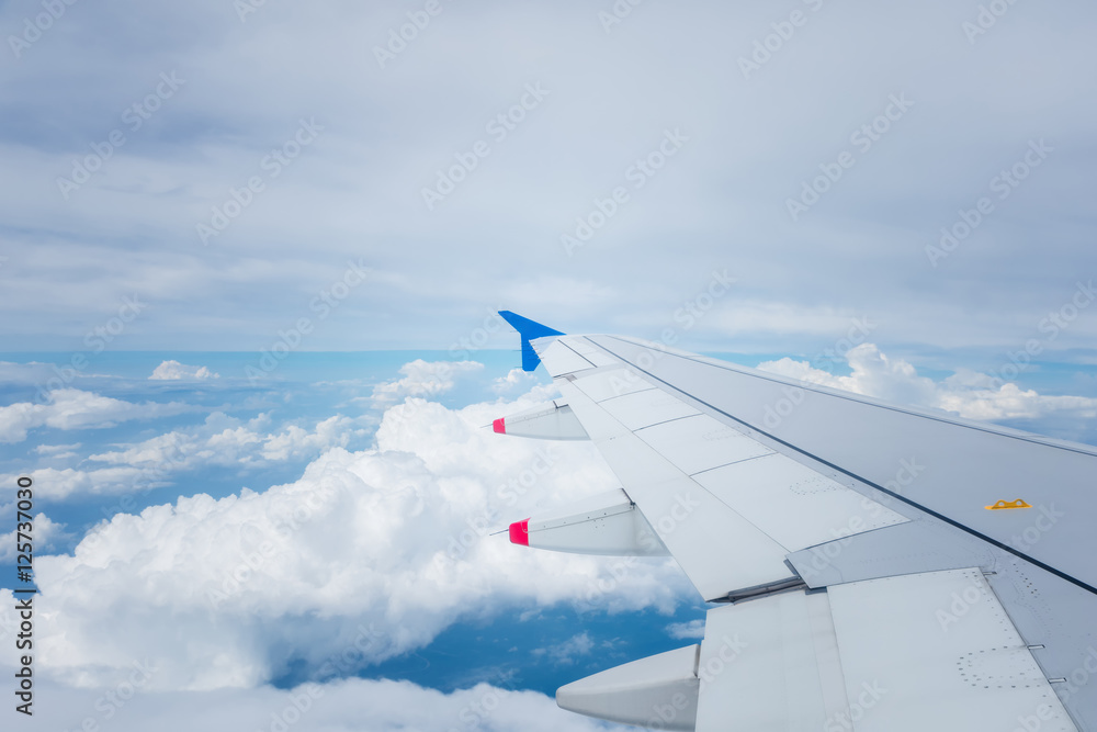 Fototapeta premium Wing of an airplane flying above white cloud