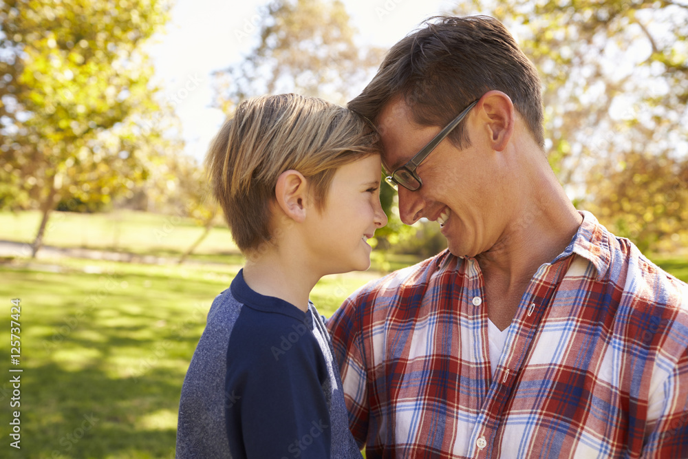 Obraz premium Father and young son in a park, heads together, side view