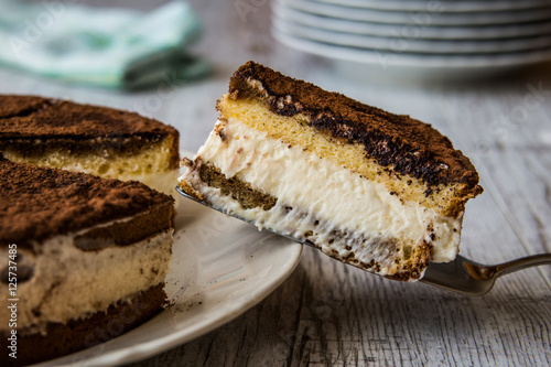 Homemade Tiramisu Cake on a white wooden surface.