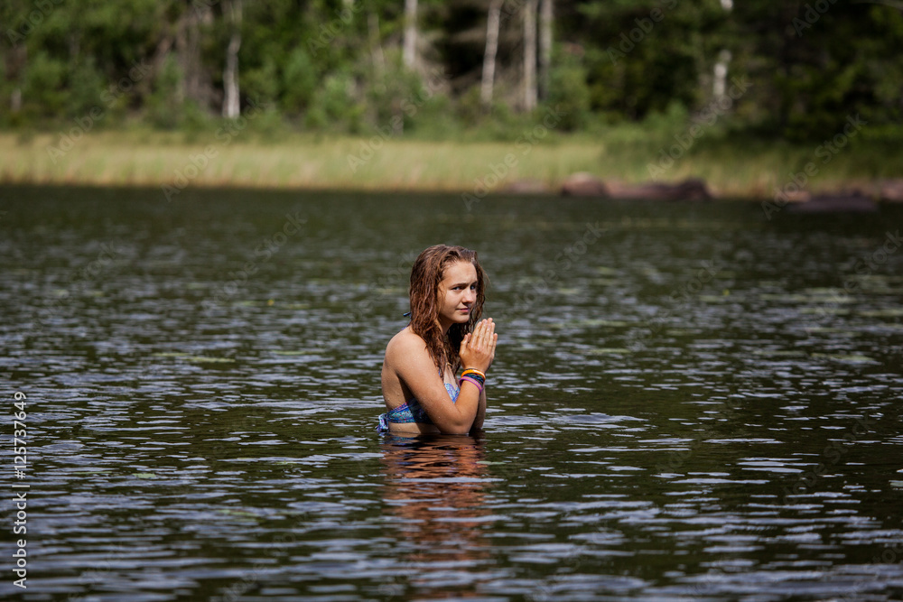 Girl preparing to dive in a Swedish lake surrounded by dense pin Girl preparing to dive in a Swedish lake surrounded by dense pin