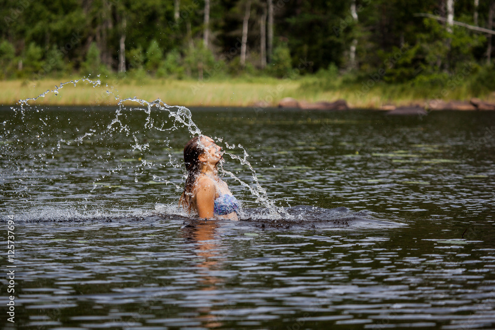 Fototapeta premium Beautiful girl splashing her hear in an Swedish forest lake