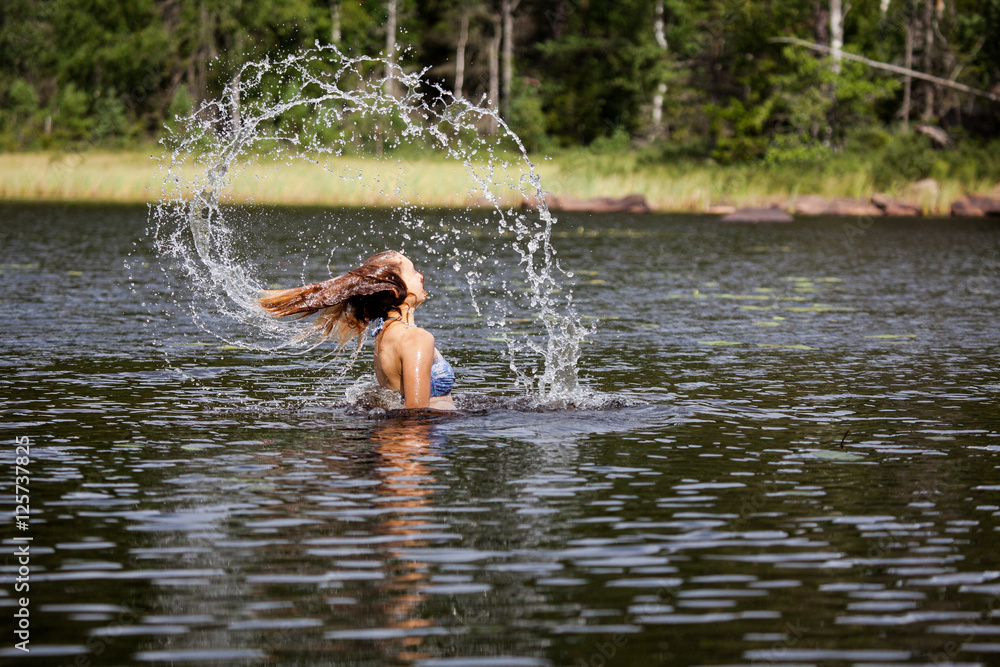 Fototapeta premium Beautiful girl splashing her hear in an Swedish forest lake