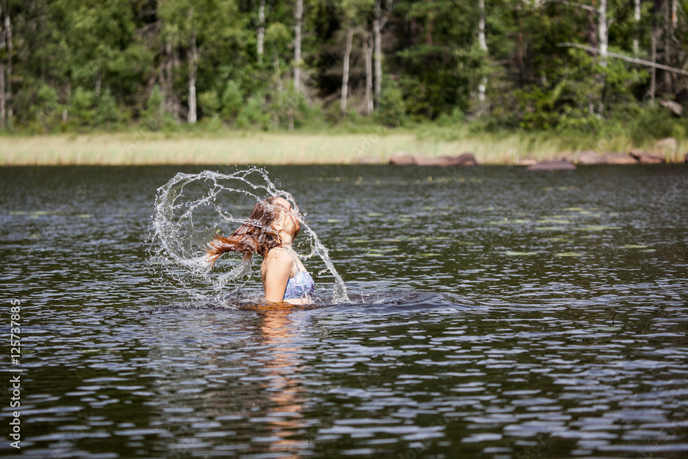 Fototapeta premium Beautiful girl splashing her hear in an Swedish forest lake