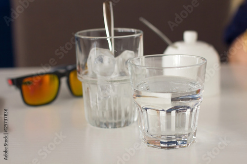 eye glasses and twoglasses of water on the table photo