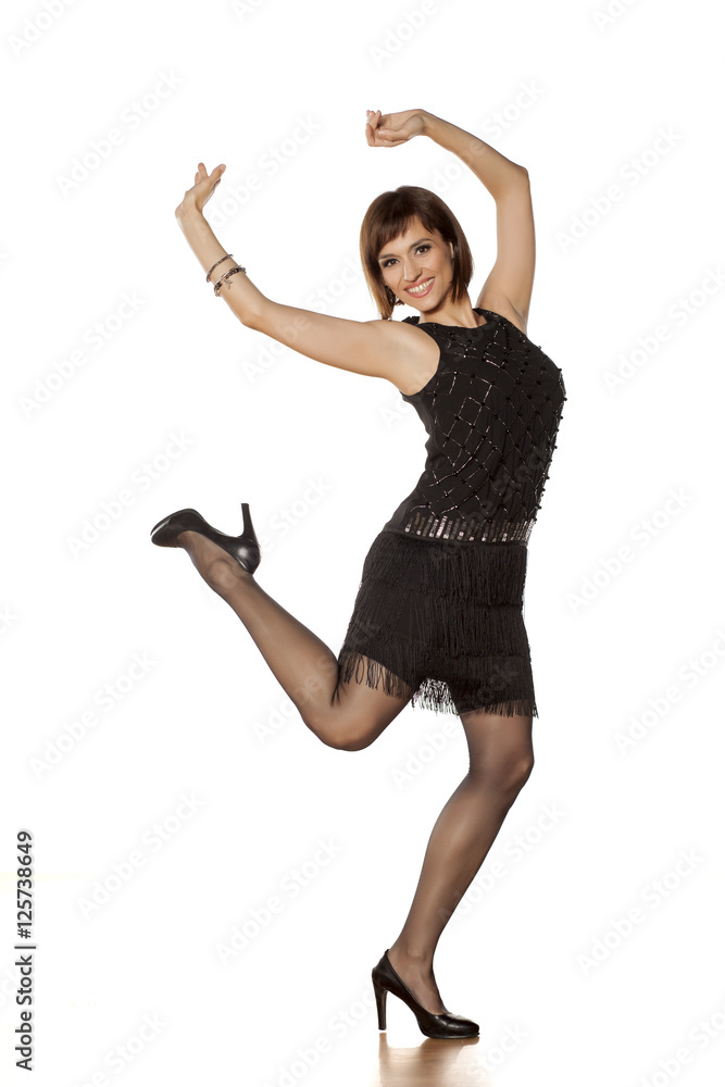happy middle-aged woman with short black dress dancing on a white background happy middle-aged woman with short black dress dancing on a white background