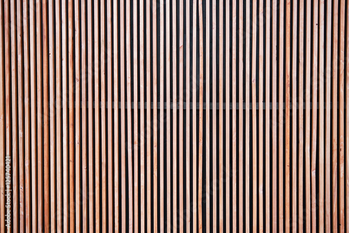 Wood cladding wall which various tone texture of wooden stripes use as partition or seamless fence in vertical line which use as building facade decoration and modern household or contemporary office. photo