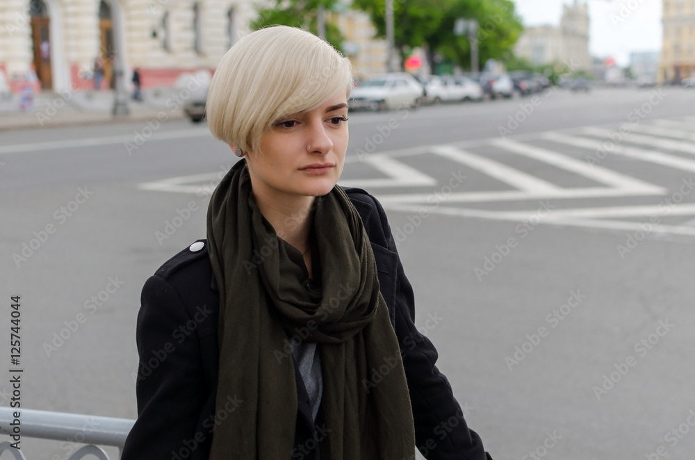 Young blonde girl walking on the city