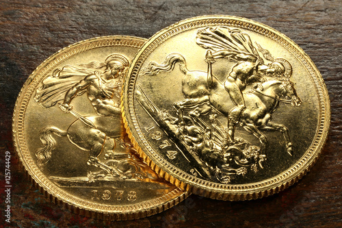 Fotografia British Sovereign gold coins on rustic wooden background