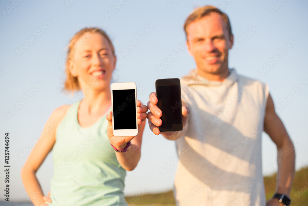 Runners on the beach holding their smartphones Runners on the beach holding their smartphones