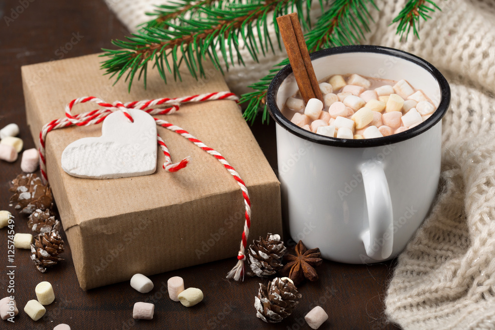 Cup with homemade Christmas hot Chocolate drink, Marshmallows and Holiday Gift on dark background. Winter time concept. Selective focus Cup with homemade Christmas hot Chocolate drink, Marshmallows and Holiday Gift on dark background. Winter time concept. Selective focus