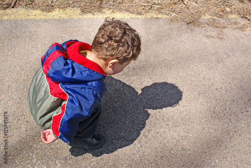 Wallpaper Mural Toddler boy bending down examining his own shadow Torontodigital.ca