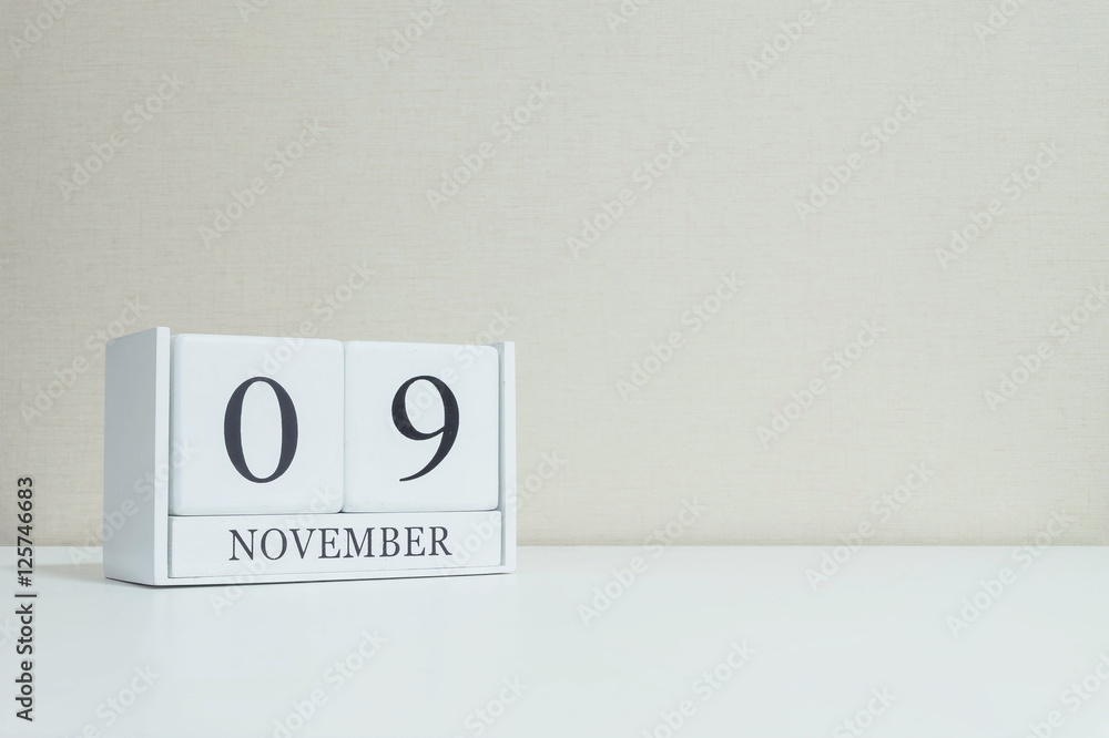 Closeup white wooden calendar with black 9 november word on blurred white wood desk and cream color wallpaper in room textured background with copy space , selective focus at the calendar Closeup white wooden calendar with black 9 november word on blurred white wood desk and cream color wallpaper in room textured background with copy space , selective focus at the calendar