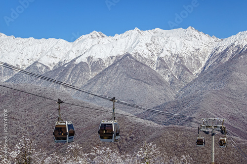 Cableway lift cabins on blue sky and snowy mountain background beautiful winter scenery © Wilding