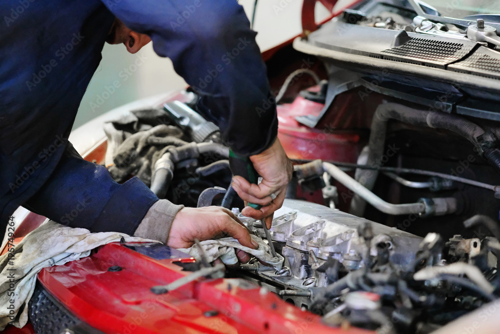 Worker repairs a car in a car repair center Worker repairs a car in a car repair center