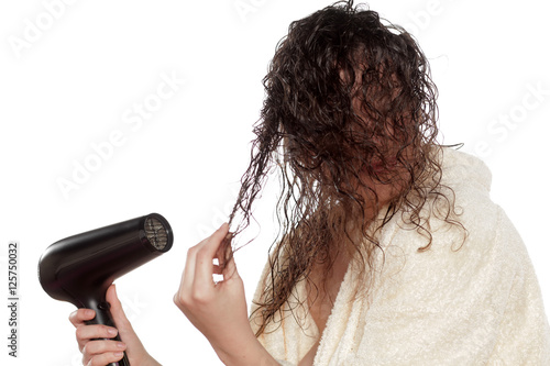 young woman dries her hair with a blow dryer