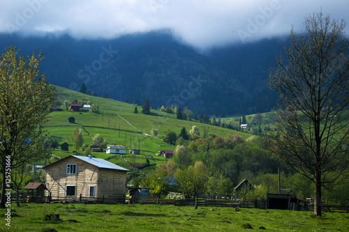 Many wooden houses in the mountains, green hills and fog.