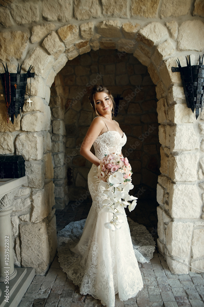 Obraz premium Gorgeous bride walks from old stone corridor