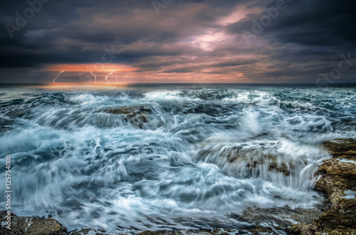 Rocks and sea. Dramatic scene with big waves and thunders. Composition of nature, Crete, Greece.