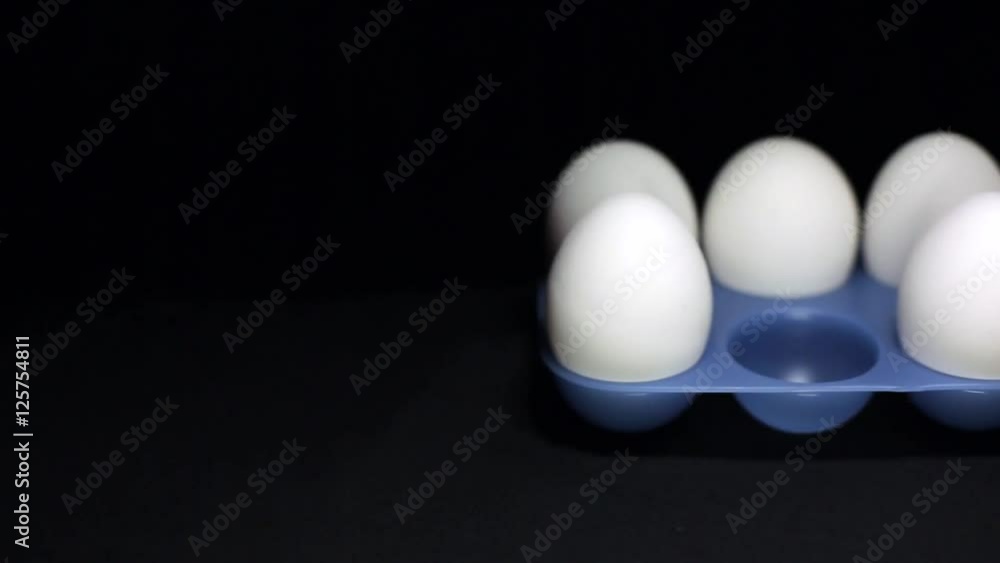A man takes white egg with his hand. Black background and the movement in the frame A man takes white egg with his hand. Black background and the movement in the frame