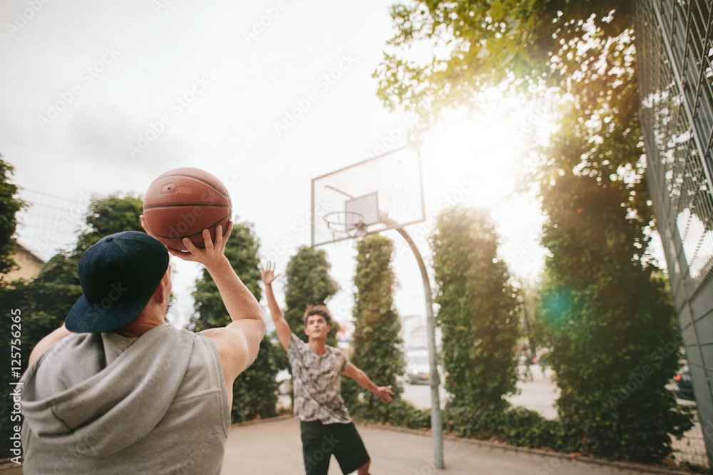 Naklejka premium Streetball players on court playing basketball.