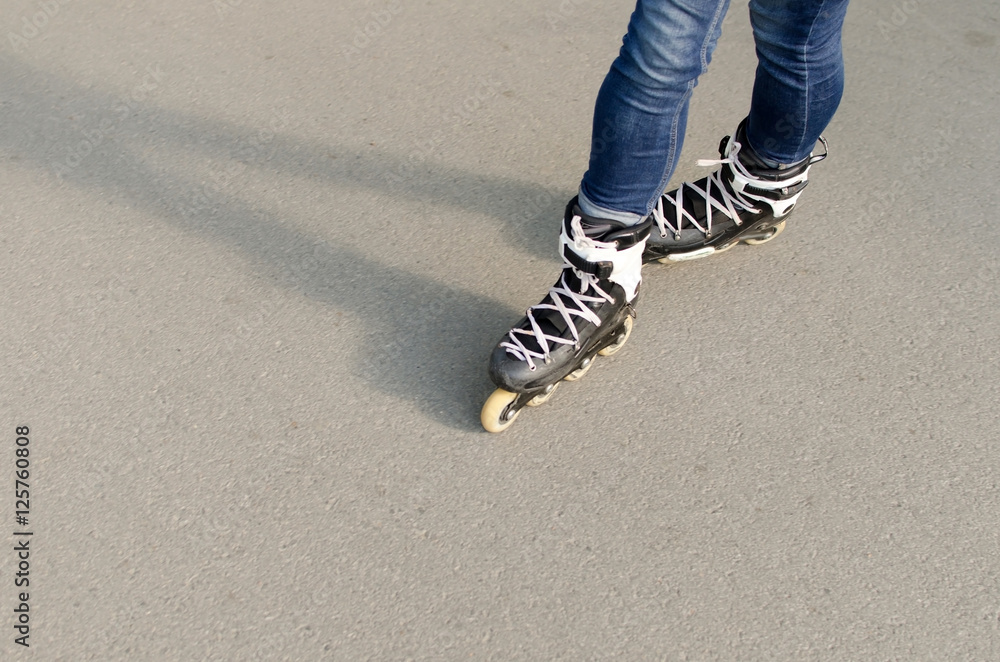 Naklejka premium Young girl with rollers in the park