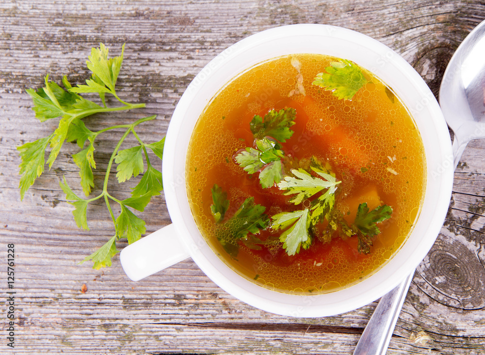 Chicken soup with carrots and parsley on wooden background Chicken soup with carrots and parsley on wooden background