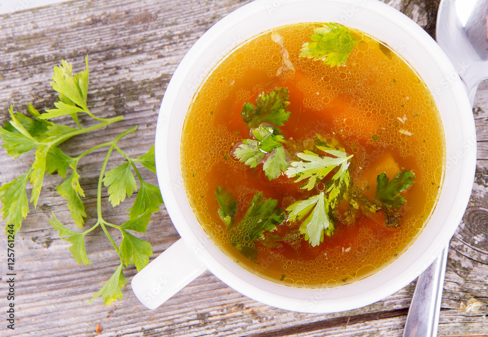 Chicken soup with carrots and parsley on wooden background Chicken soup with carrots and parsley on wooden background